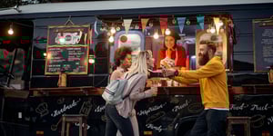 People eating food in front of a food truck.